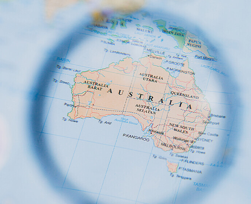 In focus illustration of Australia through magnifying glass with out of focus map outside