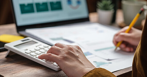 Person is calculating depreciation on their tax return for their laptop sitting in the background