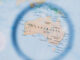 In focus illustration of Australia through magnifying glass with out of focus map outside